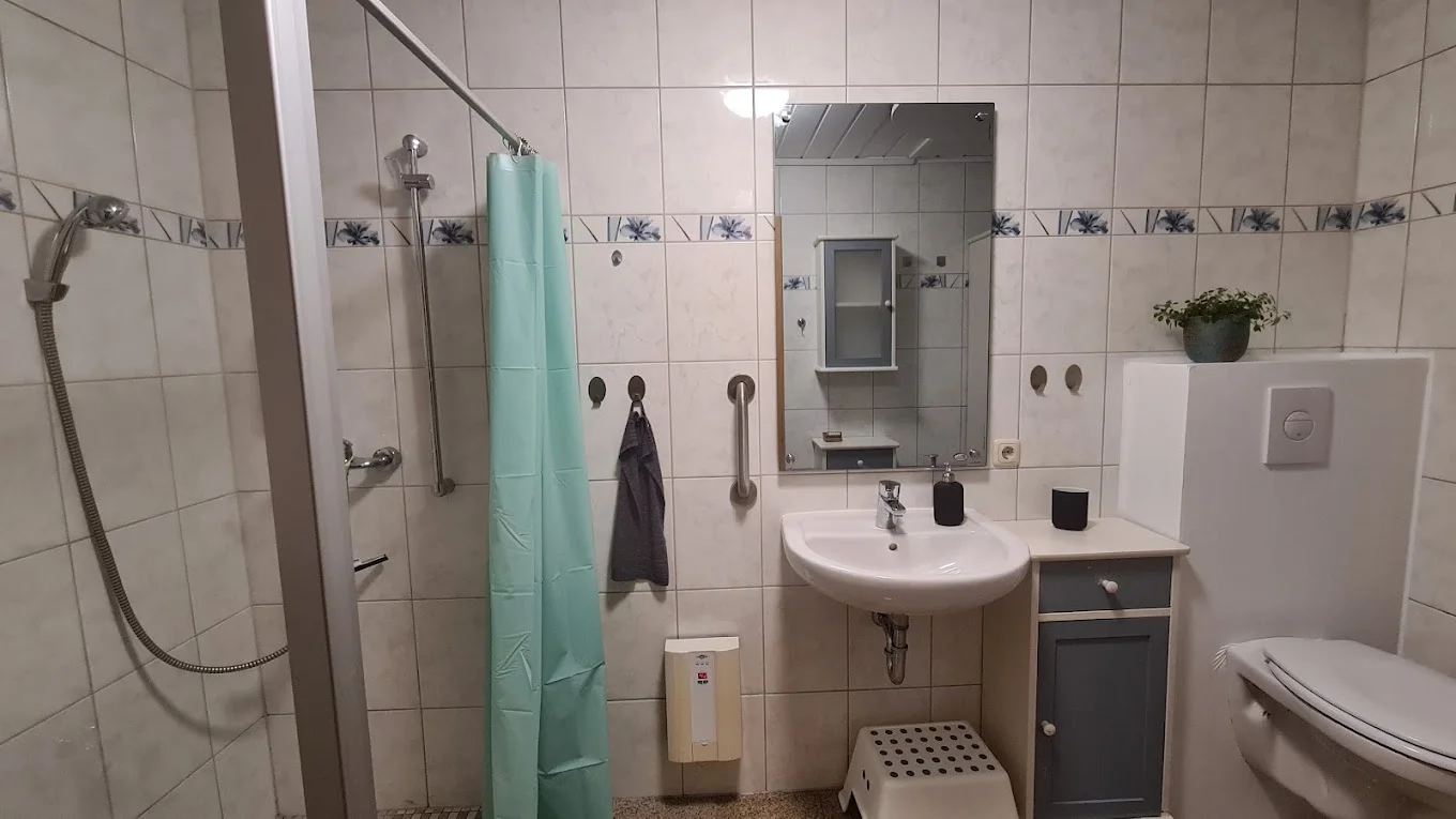 Badezimmer mit Waschbecken, Spiegel und Dusche