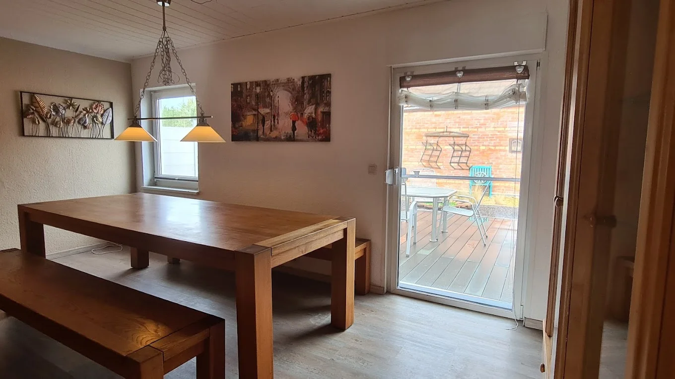 Esszimmer mit großem Holztisch und Zugang zur Terrasse