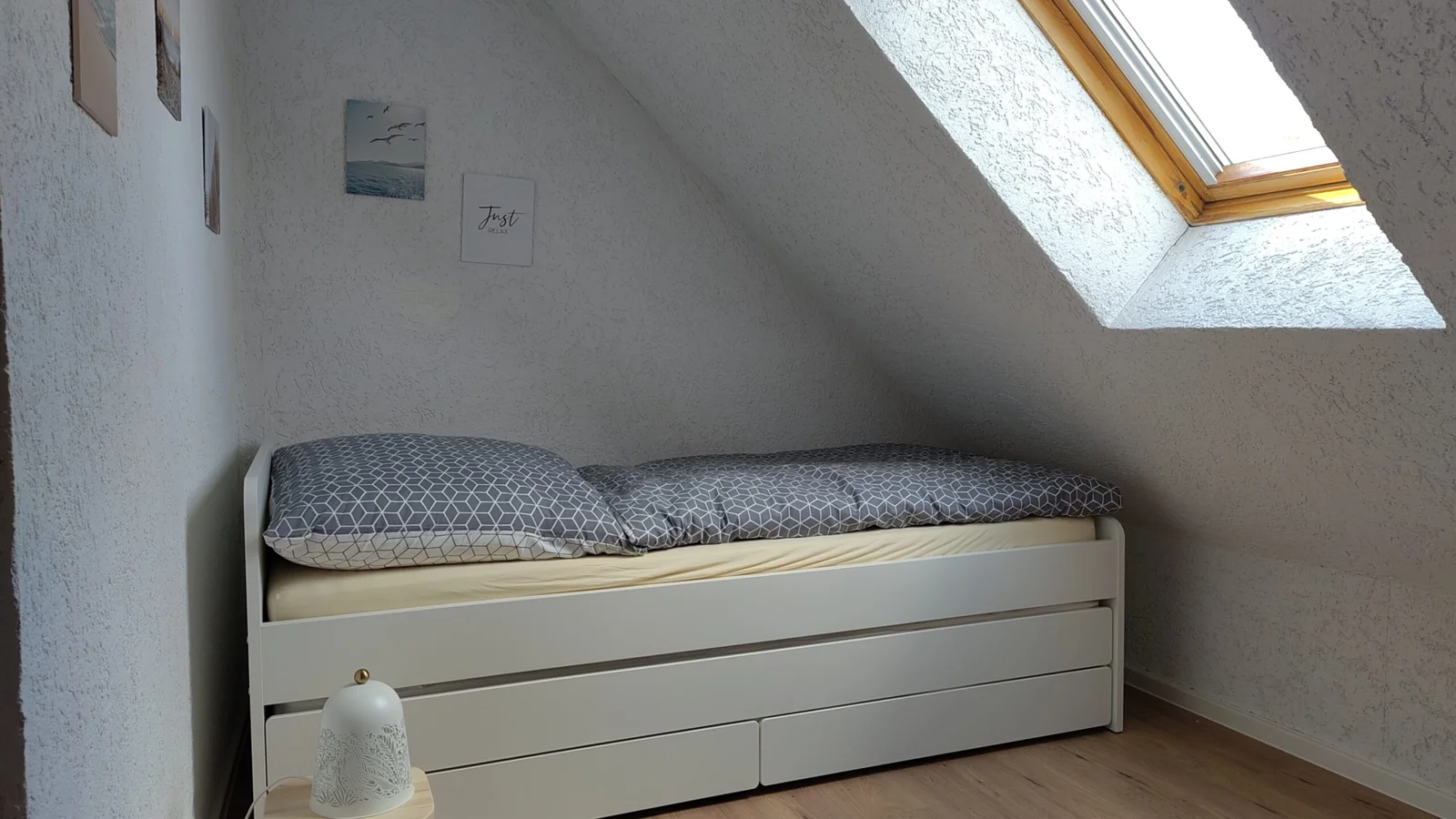 Bett unter der Dachschräge neben einem Dachfenster