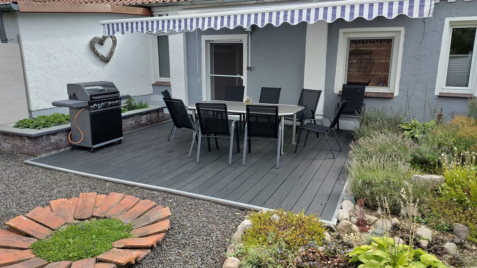 Private Terrasse mit großem Esstisch, Stühlen und Gasgrill