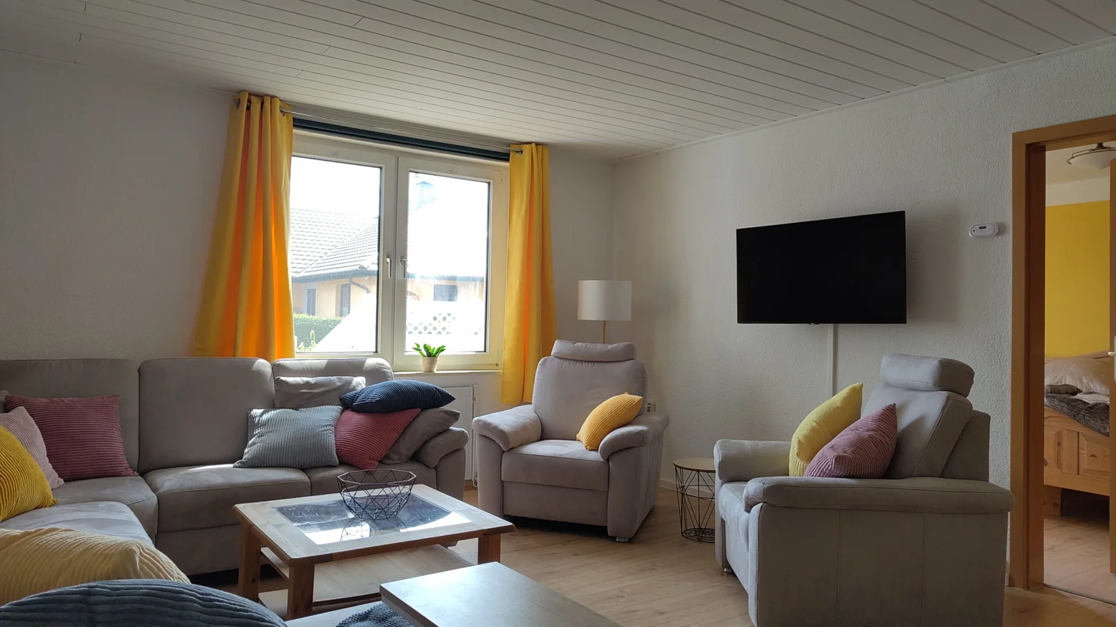 Wohnzimmer mit Sofa, Sesseln und Fernseher